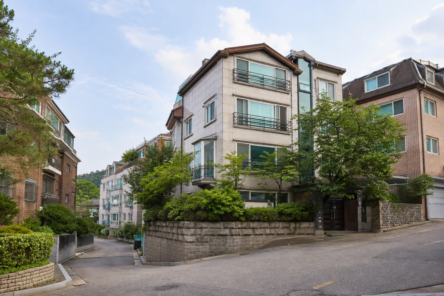Wohnstraße in Südkorea mit kleineren Mehrfamilienhäusern, Bäumen und Hanglage